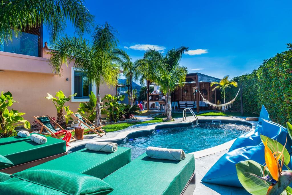 a swimming pool with chaise lounges next to a house at Antonakis Villa, Near Beach, Private Pool in Kremasti