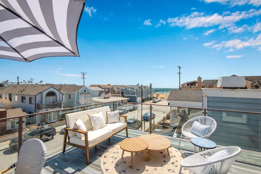 Un patio con sillas y un sofá en un balcón. en Luxury 3 Bedroom walk to Beach & Pier, en Newport Beach