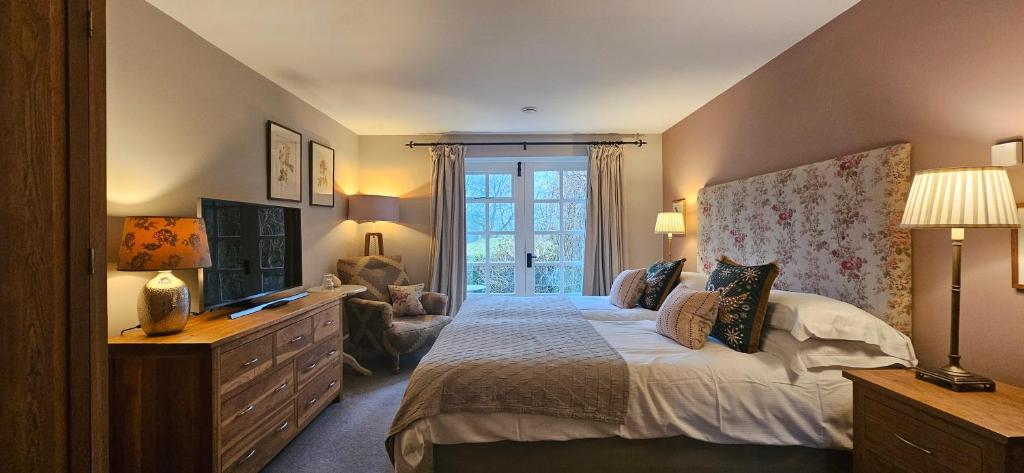 a bedroom with a bed and a dresser and a television at The Drunken Duck Inn in Ambleside