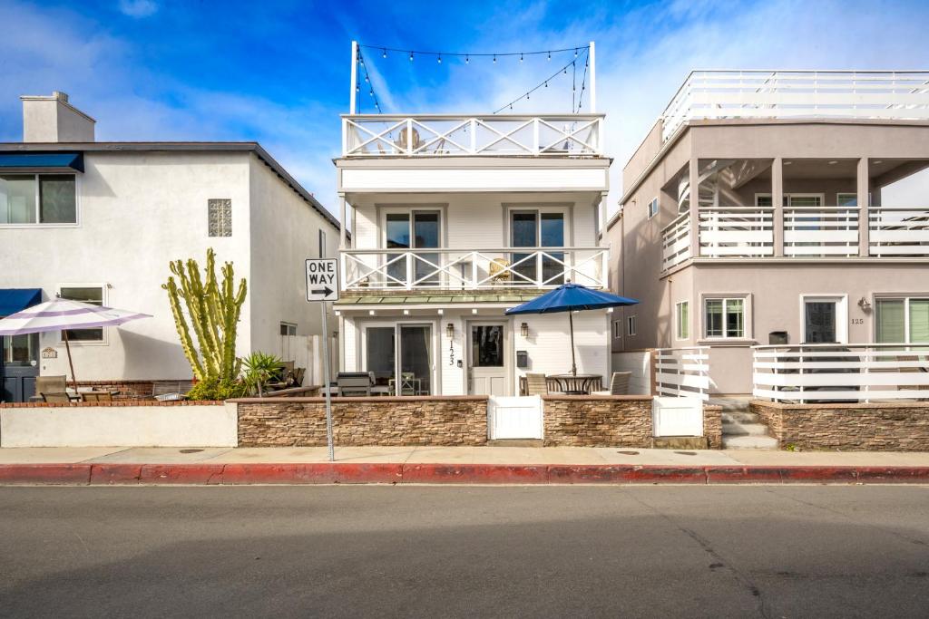 um edifício branco com um guarda-chuva azul em frente em Freshly Renovated Beach House Steps to the Beach em Newport Beach