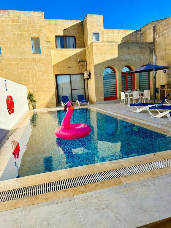 a swimming pool with a red inflatable pool toy at Dawlet ix-Xemx Gozo Farmhouse in Kerċem