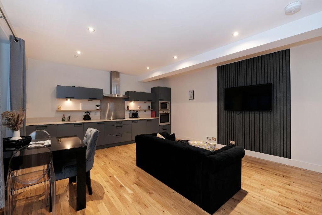 a living room with a black couch and a kitchen at One of a kind Historic 3 bedroom apartment in Aberdeen