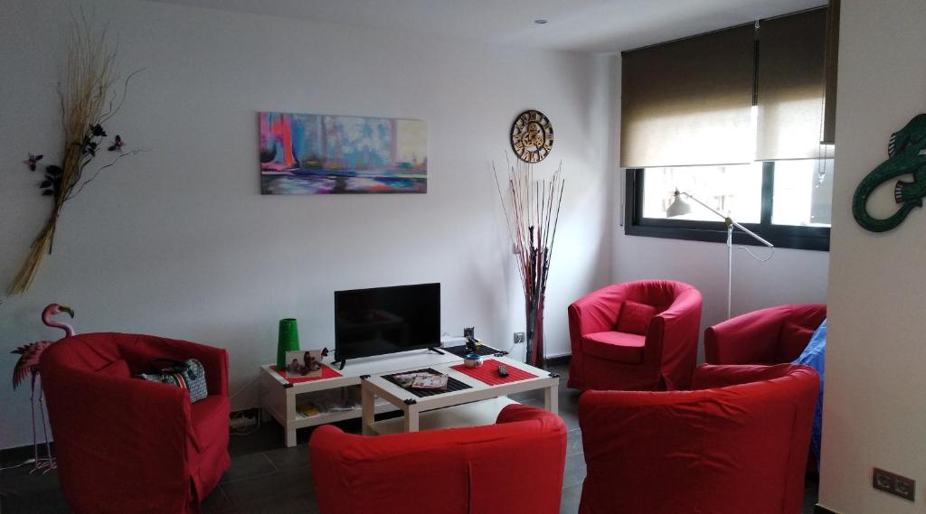 a living room with red chairs and a tv at Apartaments Oller 2 in Roses