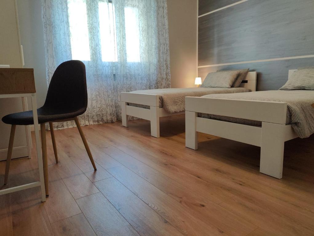 a bedroom with two beds and a chair and a window at Bed and Breakfast Cattinara in Trieste