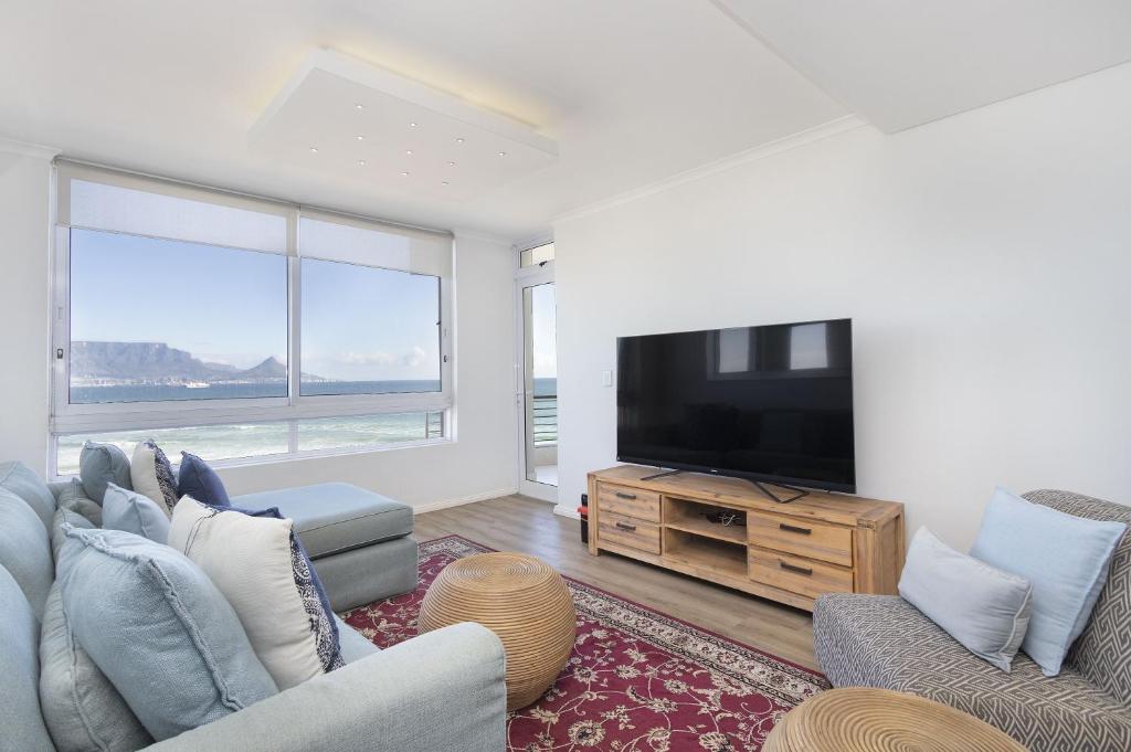 a living room with a tv and two couches at Portico 704 in Bloubergstrand