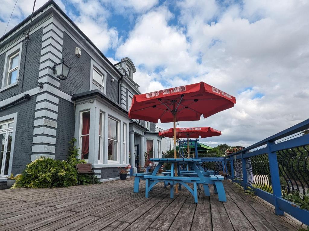 a picnic table with a red umbrella on a deck at Preston Hotel in Yeovil