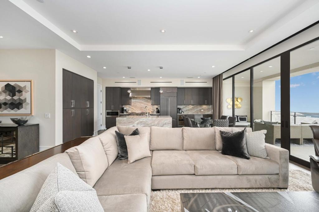 a living room with a large couch and a kitchen at True Luxury Living in Fashion Island with Elevator and Ocean Views in Newport Beach