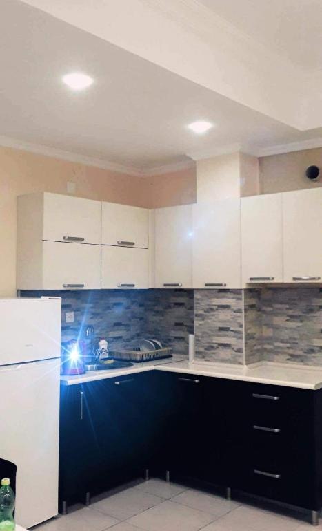 a kitchen with white cabinets and a black counter top at apartment Leyla in Batumi