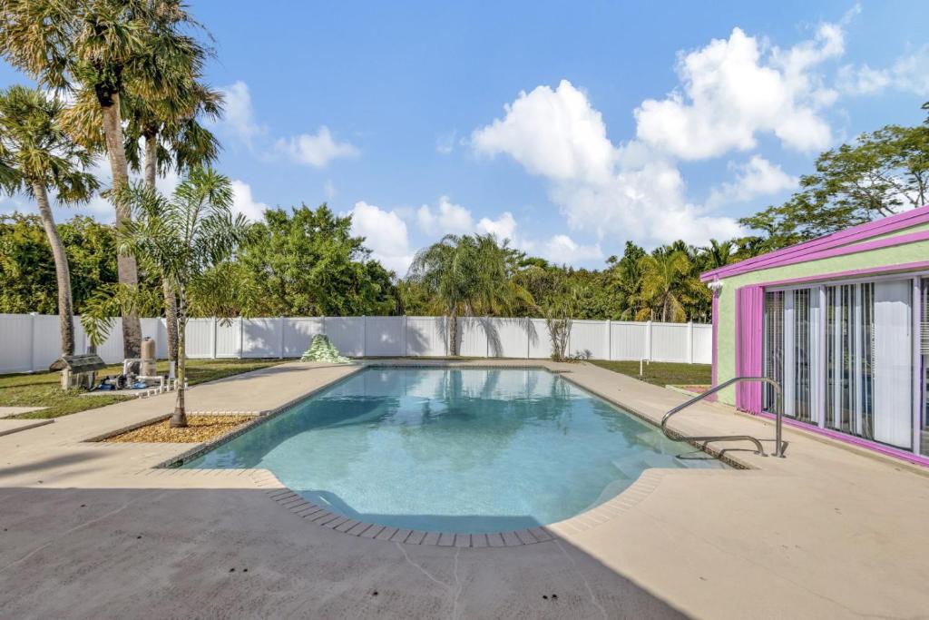- une piscine en face d'une maison rose dans l'établissement 2 BR Jensen Beach Tropical Resort, à Fort Pierce