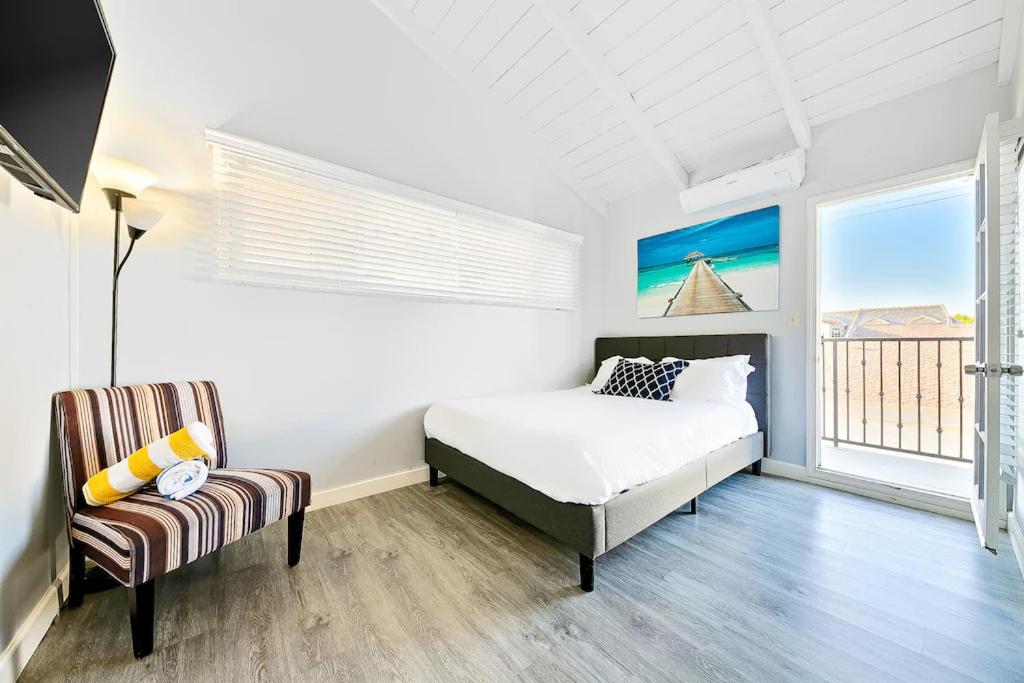 ein weißes Schlafzimmer mit einem Bett und einem Stuhl in der Unterkunft 4 Bedroom Across from the Beach and Boardwalk in Newport Beach