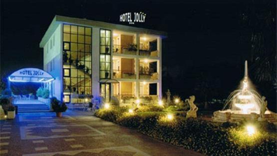 un bâtiment avec des lumières devant lui la nuit dans l'établissement Hotel Jolly, à Modugno