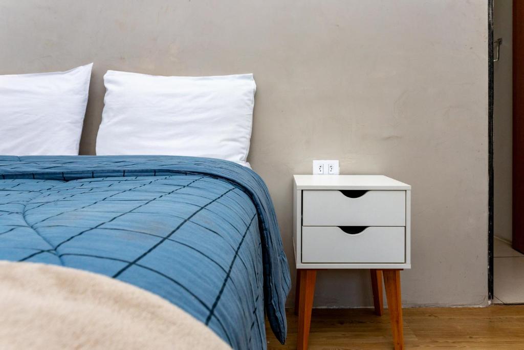 a bed with a blue comforter and a side table at CykelHaus Studios in Sao Paulo