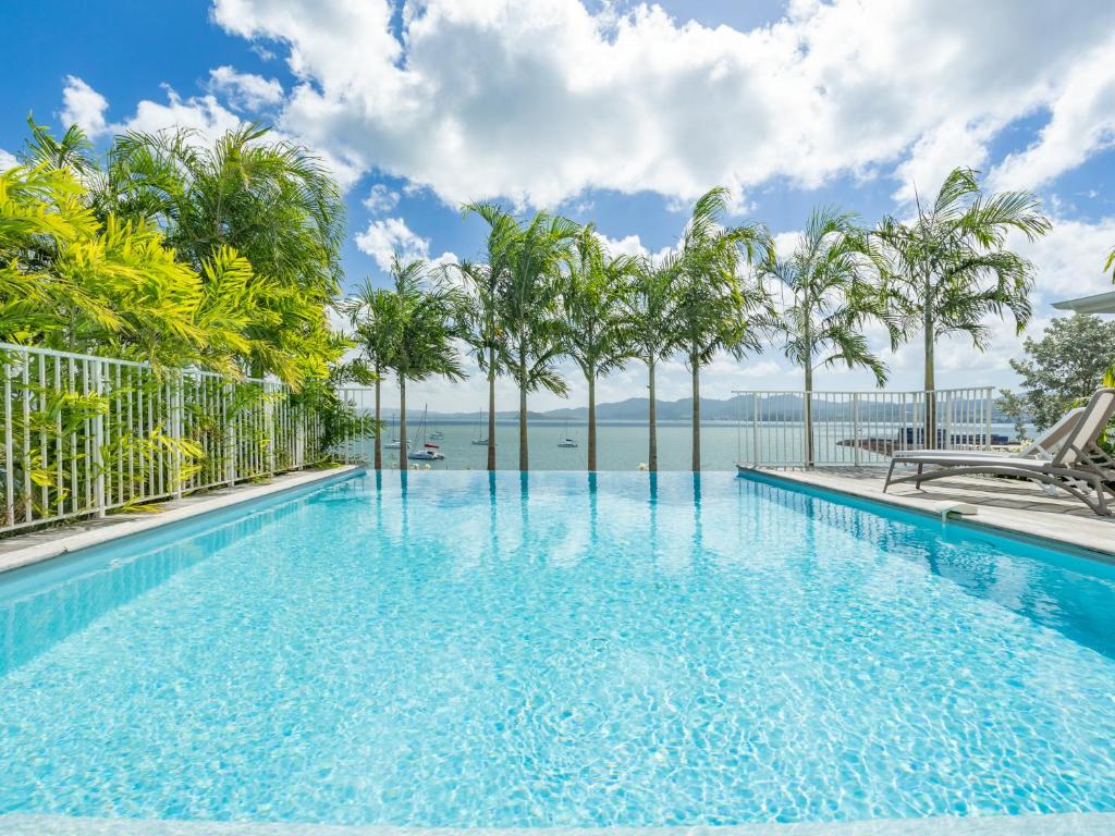 een zwembad met uitzicht op het water en de palmbomen bij B&B HOTEL Fort-de-France in Fort-de-France