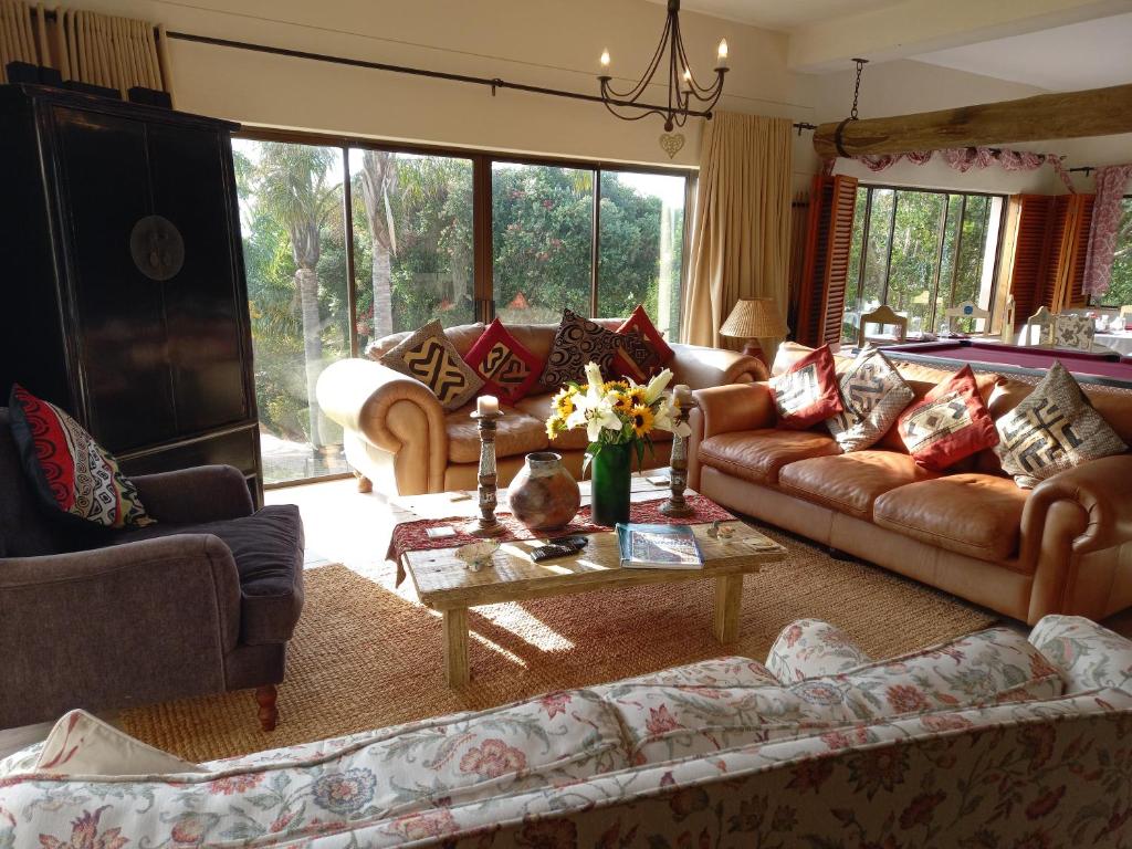 a living room with couches and a table with flowers at Tidal Retreat in Plettenberg Bay