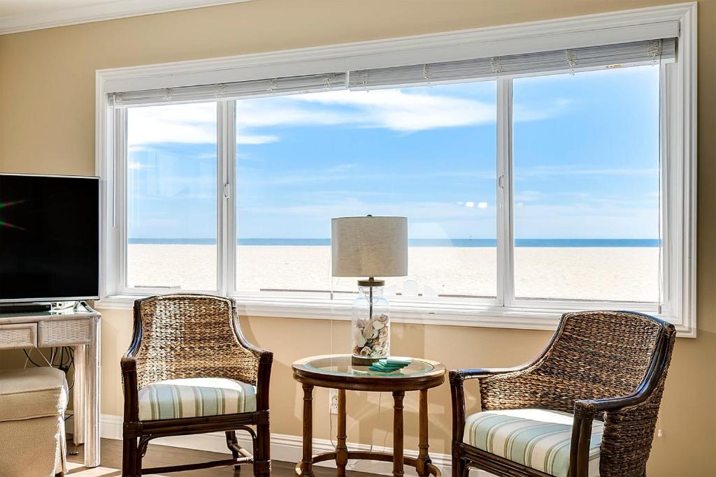 ein Wohnzimmer mit 2 Stühlen, einem Tisch und einem Fenster in der Unterkunft TWO BEACHFRONT BUNGALOWS ON THE SAND IN Newport Beach in Newport Beach