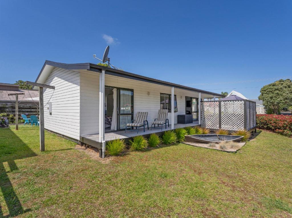 a white house with a porch and a yard at Beach Life - Whangamata Holiday Home in Whangamata
