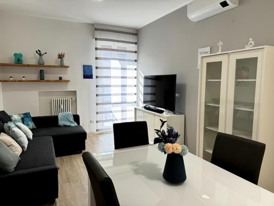 een woonkamer met een witte tafel en een zwarte bank bij [Monza Centro in 10 Min]Comfort Suite XL in Monza