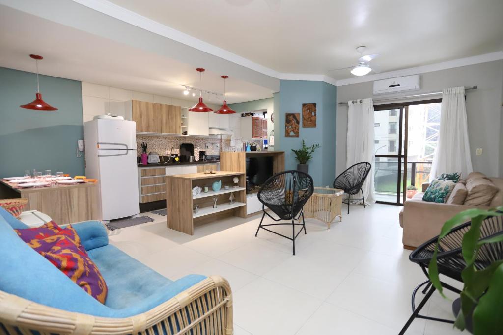 Apartamento Praia do Tombo Guarujá 120m do mar في غوارويا: مطبخ وغرفة معيشة مع أريكة وكراسي