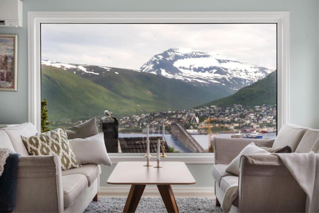 een woonkamer met uitzicht op een met sneeuw bedekte berg bij House with iconic view in Tromsø