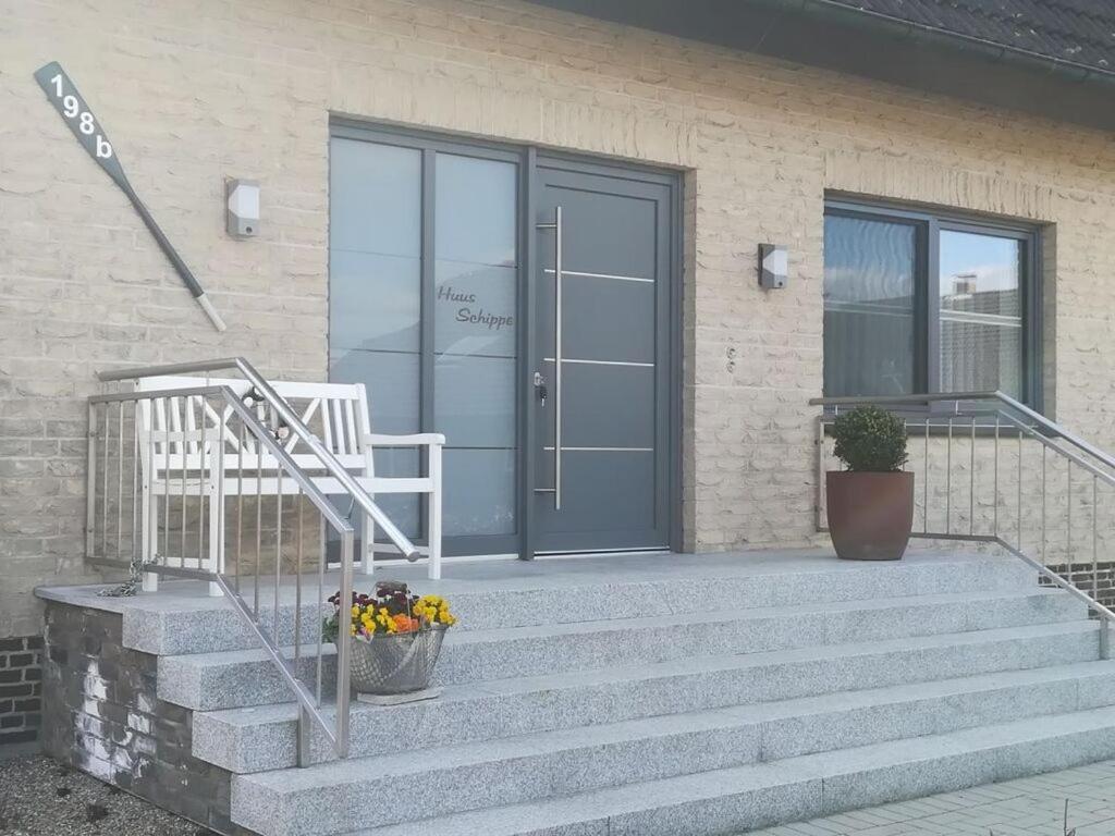 a front door of a house with stairs and flowers at Huus Schippe "Stockholm" in Maasholm-Bad