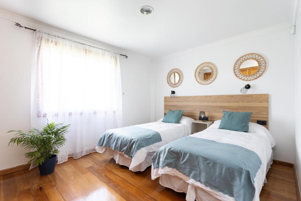 zwei Betten in einem Schlafzimmer mit weißen Wänden und Holzböden in der Unterkunft Casa Lali Habitación 2 in La Laguna