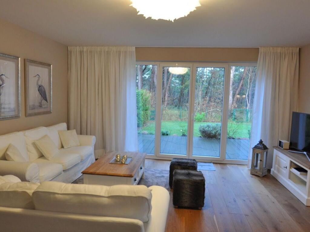Una sala de estar con muebles blancos y una gran ventana. en Holiday house dune forest b, en Dierhagen