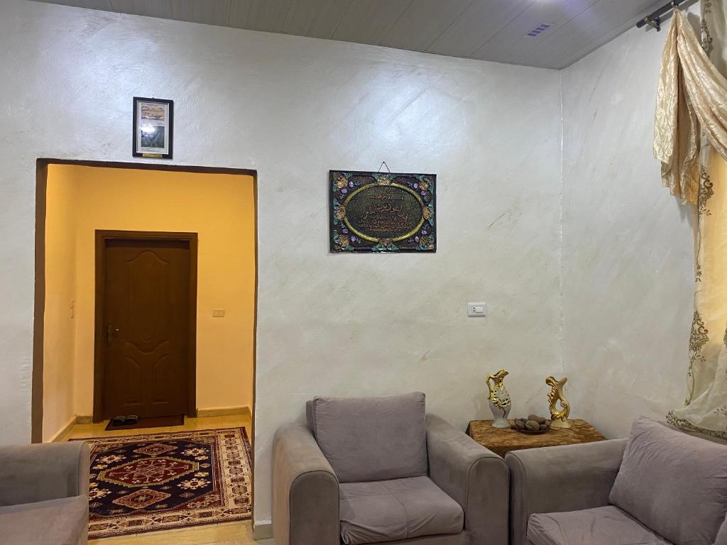 a living room with two chairs and a door at Traveler's house in Jerash