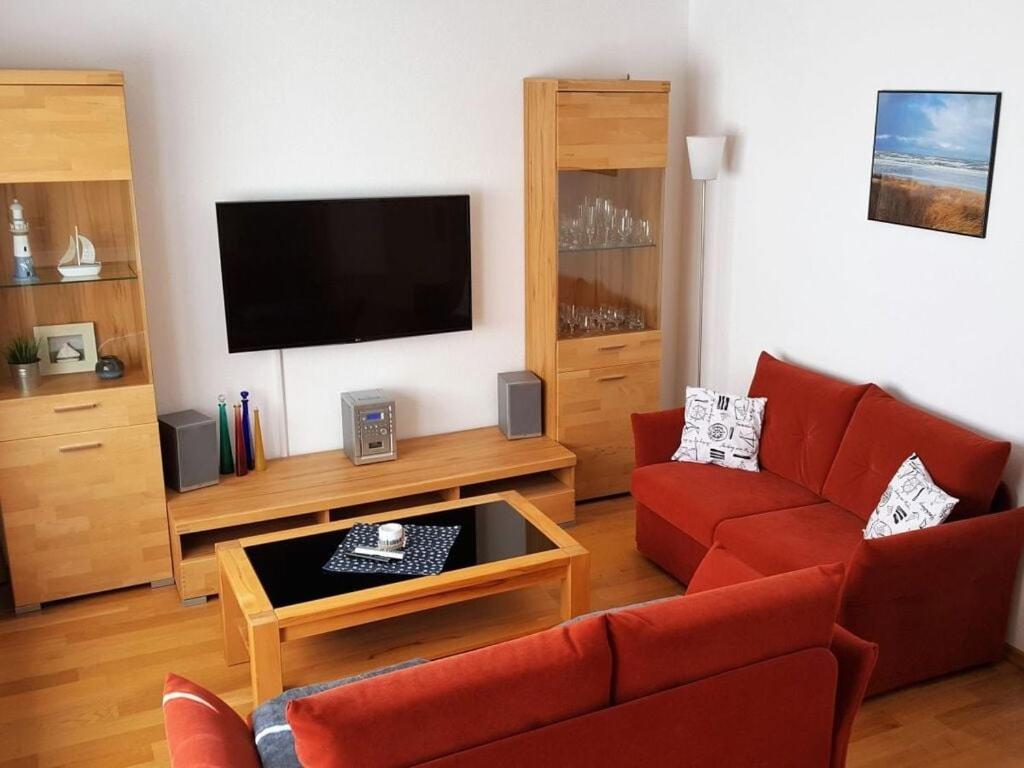 a living room with a red couch and a flat screen tv at Holiday apartment wind force 8 in Langeoog