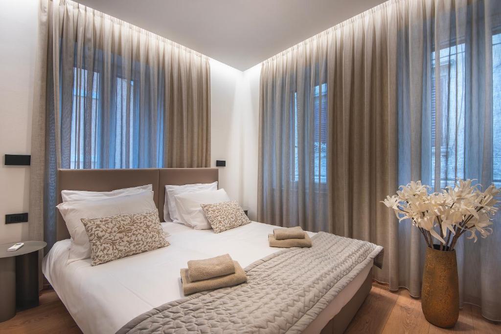 a bedroom with a large white bed with windows at Arta Apartments City Center - with Private Parking in Pula