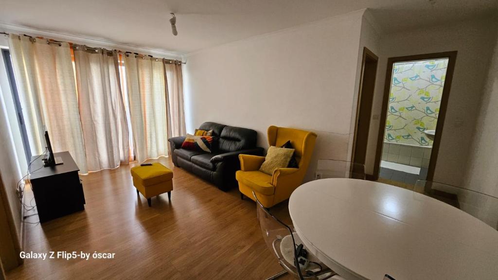 ein Wohnzimmer mit einem schwarzen Sofa und gelben Stühlen in der Unterkunft Ap Central Chic in Odivelas