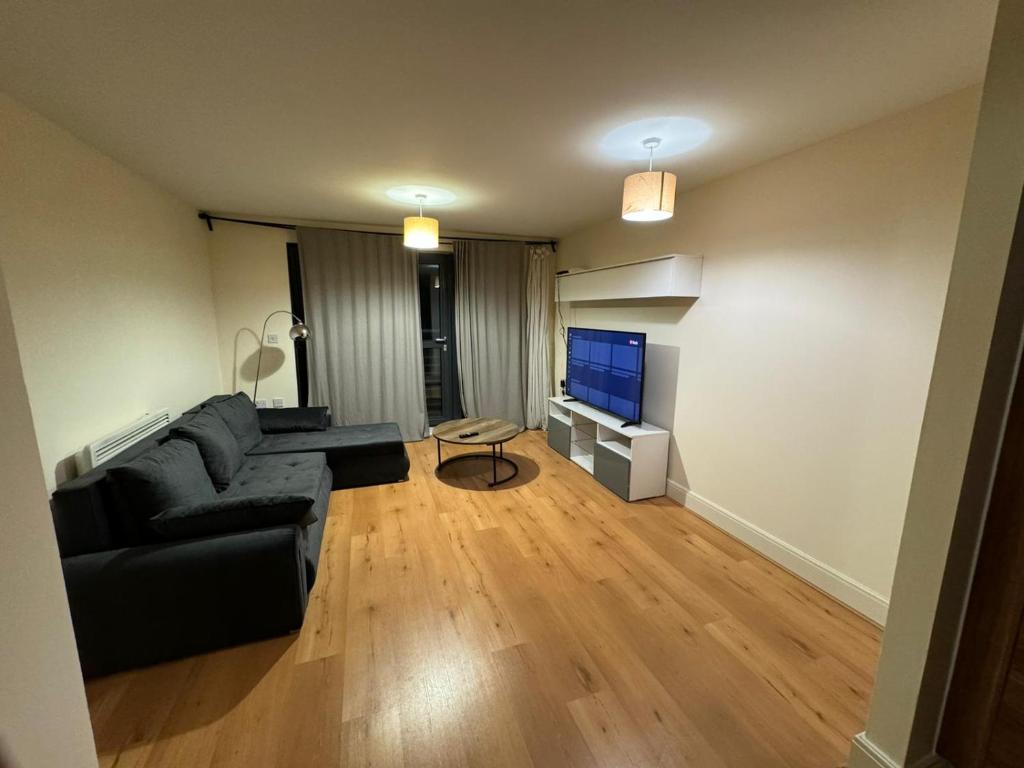 a living room with a black couch and a television at Bermondsey by Tower Bridge in London
