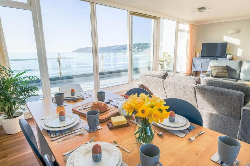 a dining room with a table with yellow flowers on it at Stunning seaside penthouse apartment with balcony in Newlyn