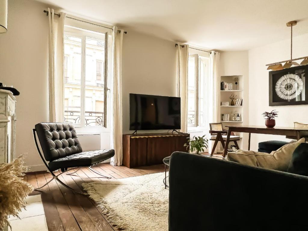 a living room with a couch and a television at Why Paris ? Why Montmartre ? in Paris