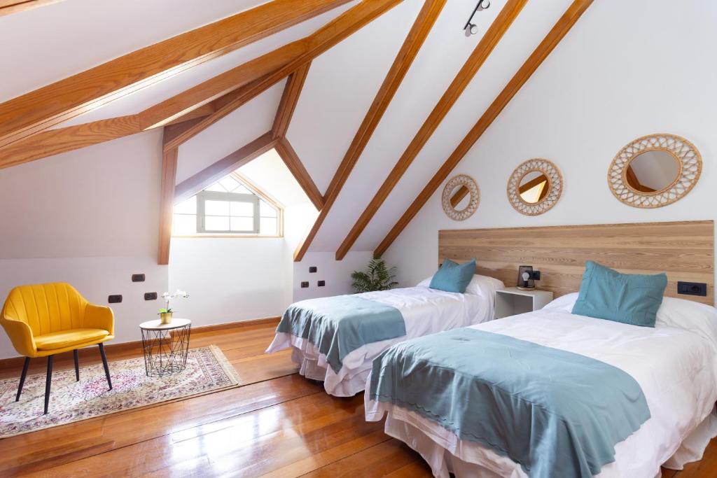 a attic bedroom with two beds and a chair at Casa Lali Habitación baño compartido in Las Lagunas