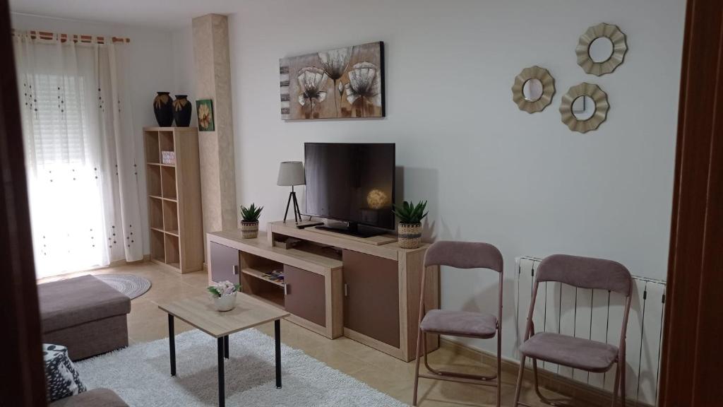 uma sala de estar com uma televisão de ecrã plano e cadeiras em Casa Preguntoiro em Vilagarcía de Arousa