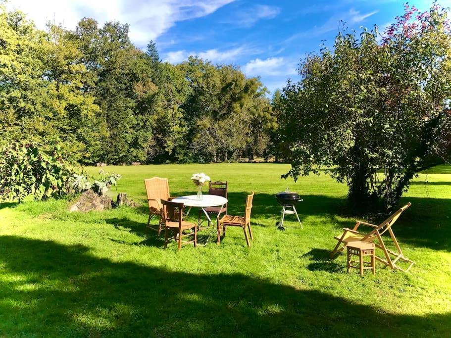 Maison des Séquoias - Parc 1 hectare- في Veyrac: طاولة وكراسي في العشب في حقل