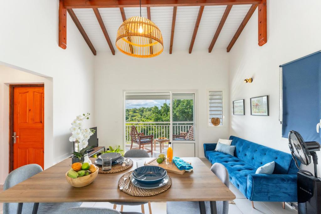een woonkamer met een tafel en een blauwe bank bij Séjour nature dans un écrin de modernité in Les Abymes
