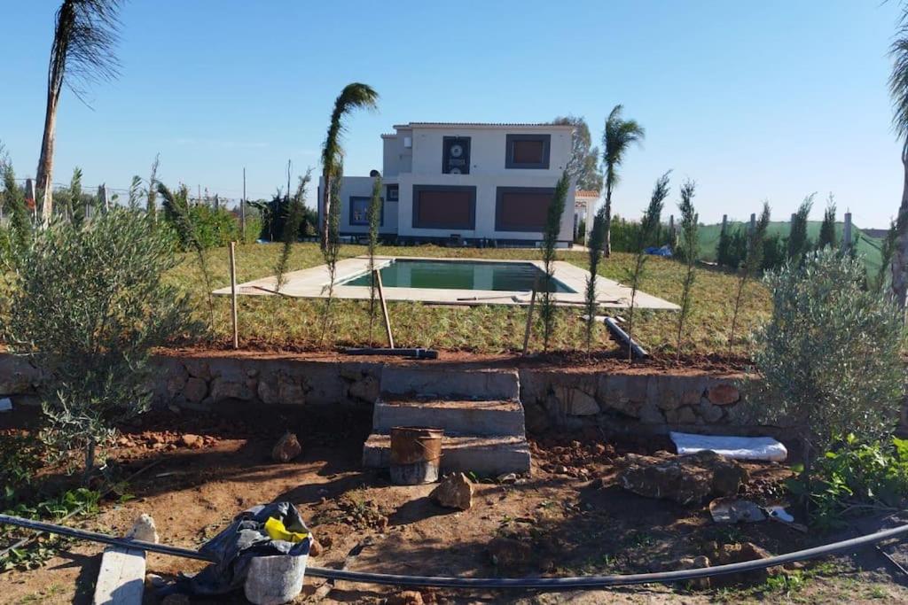 un cortile con una casa e una piscina di Maison+piscine dans une ferme benslimane a Ben Slimane