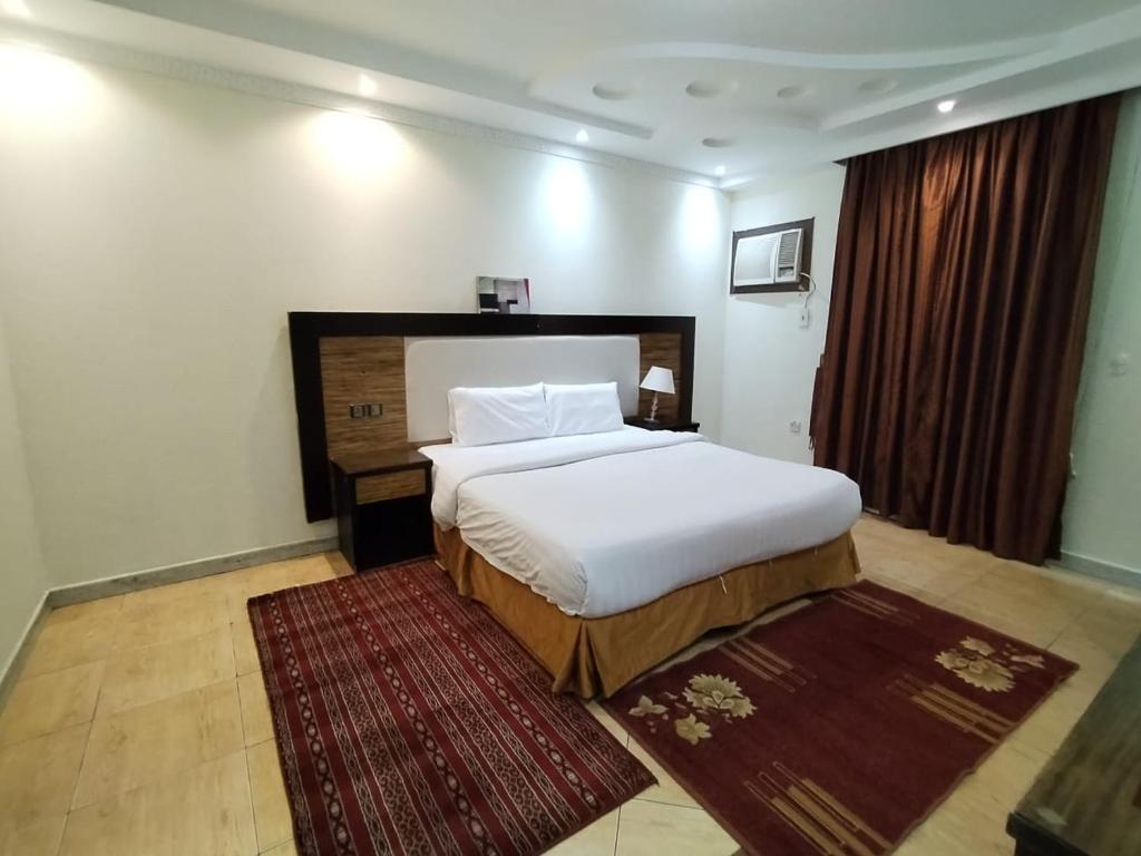 شقق الاحلام بحراء للايجار الشهري والسنوي في جدة: غرفة نوم بسرير ابيض وسجادة حمراء