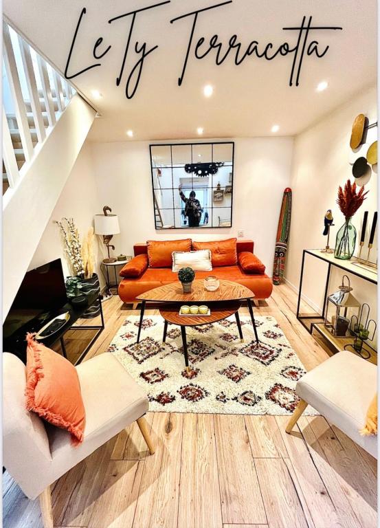 a living room with an orange couch and a table at Le TyTerracotta de juju, en plein cœur de la ville in Saint-Brieuc