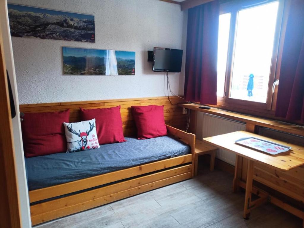 a room with a bed with red pillows and a television at Résidence Sikkim - Studio pour 2 Personnes 764 in Aime-La Plagne