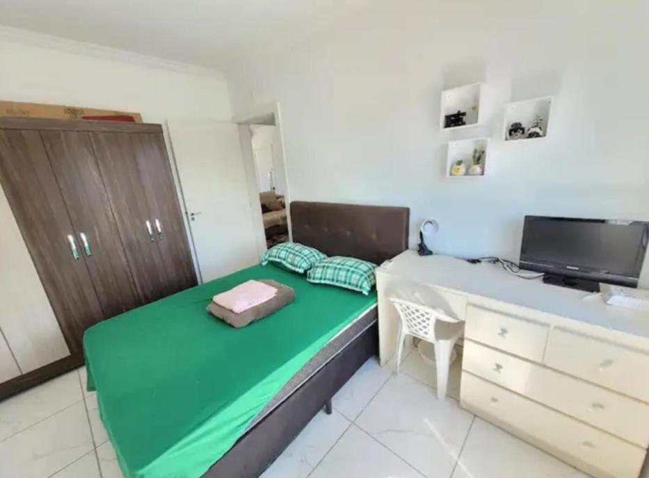 a small bedroom with a green bed and a desk at Apartamento novo e completo! in Brusque