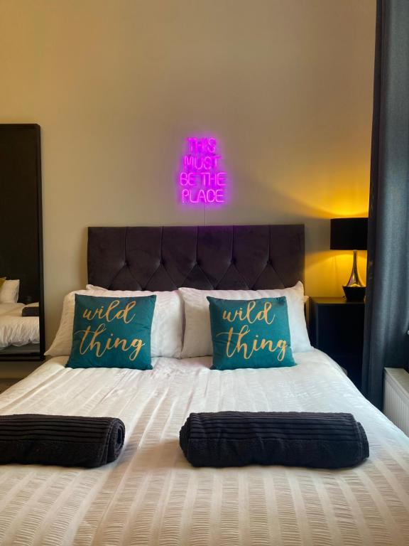 a bed with two pillows and a neon sign above it at Anfield city break in Liverpool