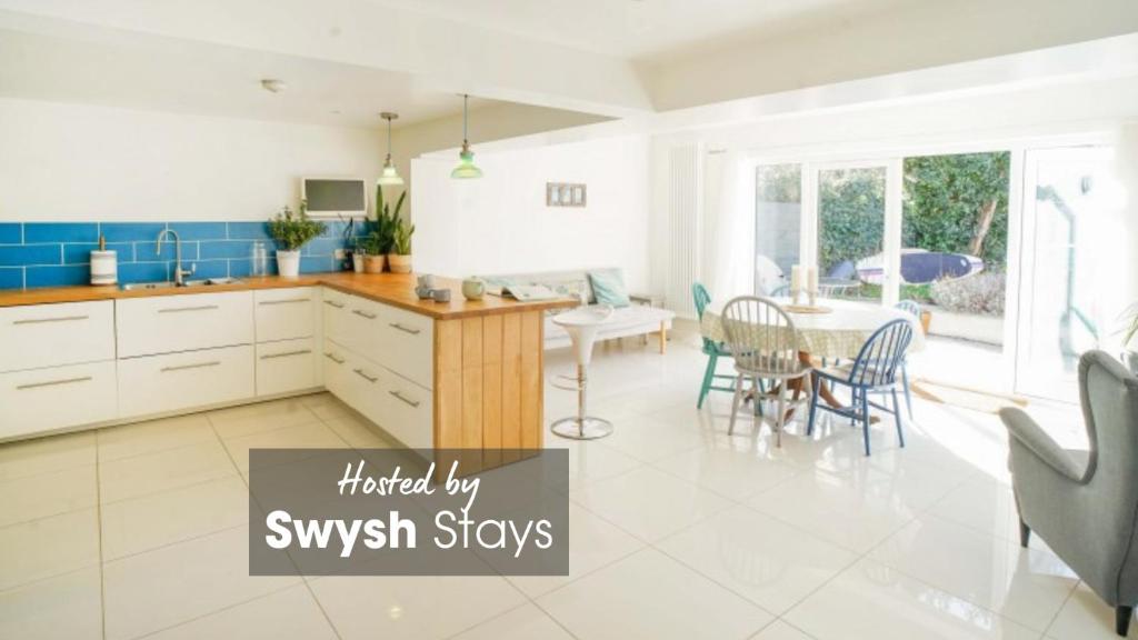 a kitchen with white cabinets and a table with chairs at Seashell, Bembridge in Bembridge