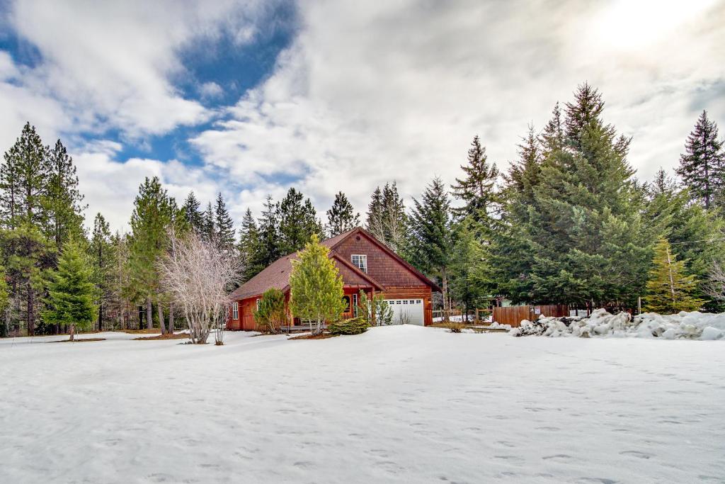 una casa roja en la nieve con árboles en Forested Cle Elum Home with Trail Access and Deck, en Cle Elum