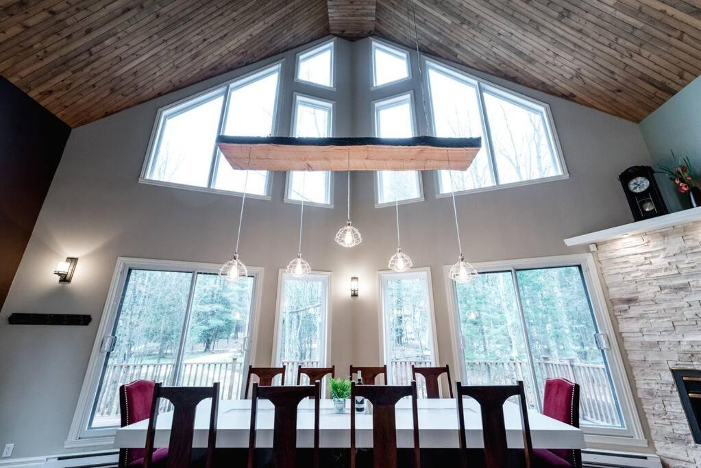 a dining room with a table and chairs and windows at Le Fitchbay in Magog-Orford