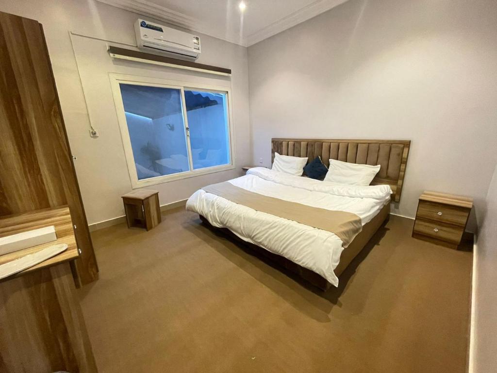 Schlafzimmer mit einem Bett mit weißer Bettwäsche und einem Fenster in der Unterkunft شاليه منتجع هدا الأحلام 