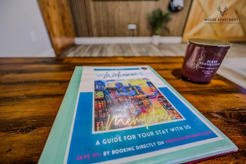 ein Buch auf einem Tisch mit einer Tasse in der Unterkunft The Moose at Memphis Downtown &amp; Victorian Village in Memphis