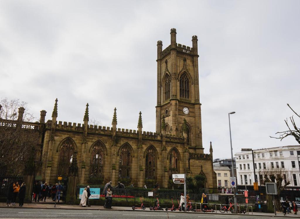 a large cathedral with a clock tower in a city at St Luke's 2 in Liverpool