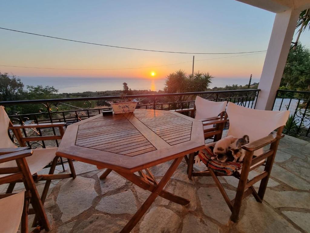 una mesa y sillas en un balcón con un perro. en Infinity View Villa, en Koríthion